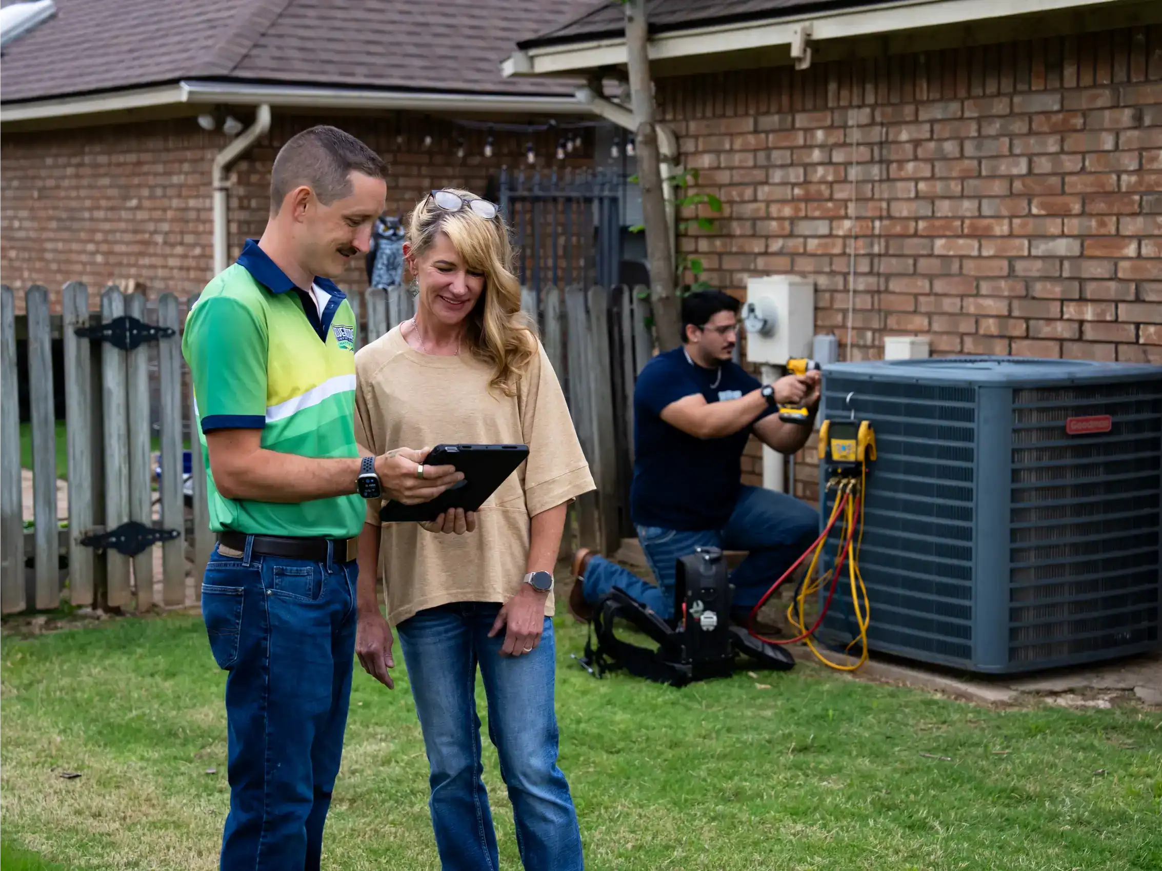 Riverside technicians reviewing an outdoor unit with a homeowner