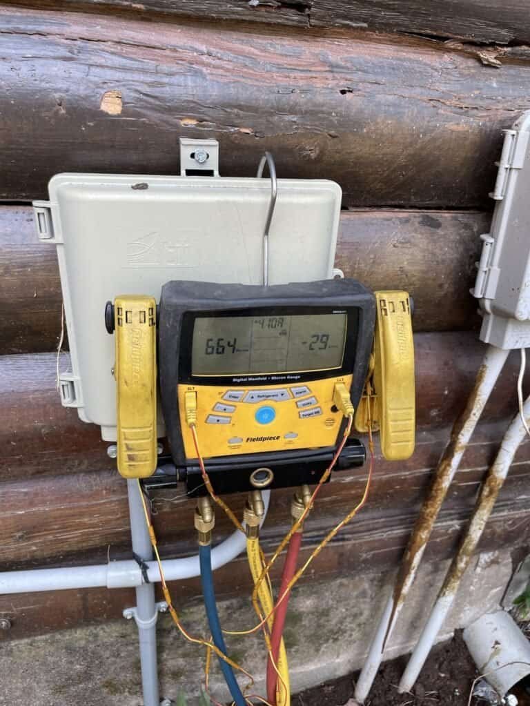 Digital gauges connected at the outdoor unit during a refrigerant line replacement in Cedarville