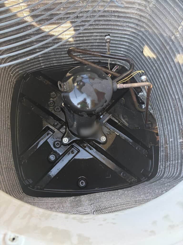 Inside of a Fort Smith AC condenser after service, with debris cleared from the base pan