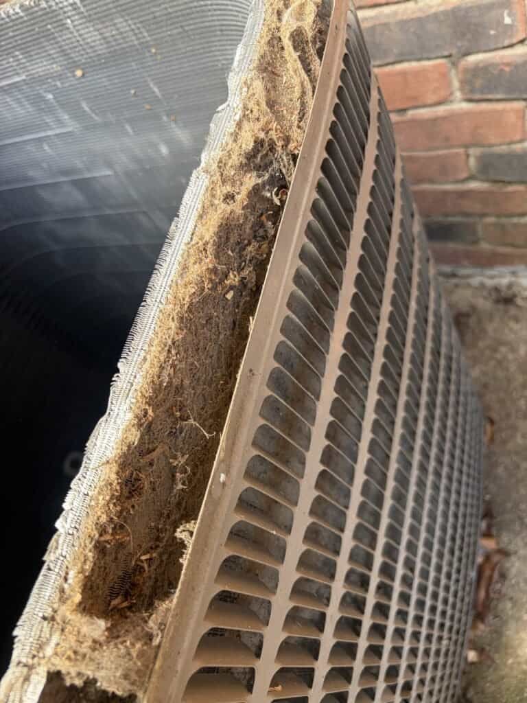 Lint and debris packed between the layers of an outdoor AC coil in Fort Smith, Arkansas