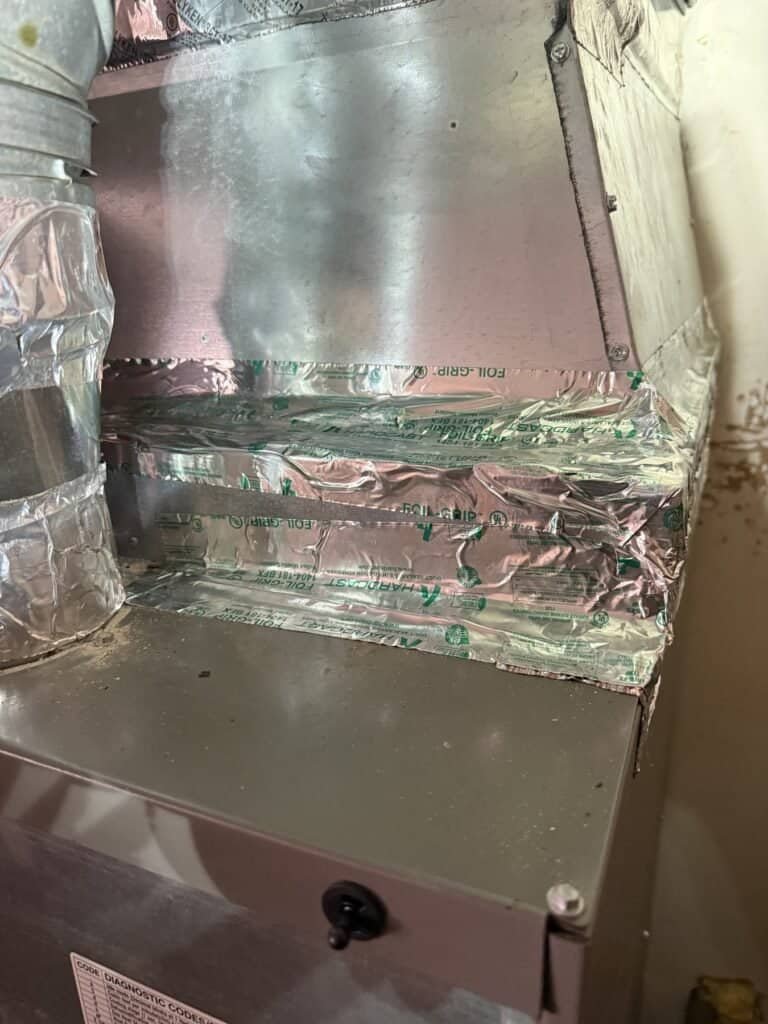 New evaporator coil cabinet sealed with foil tape above a furnace in a Fort Smith home