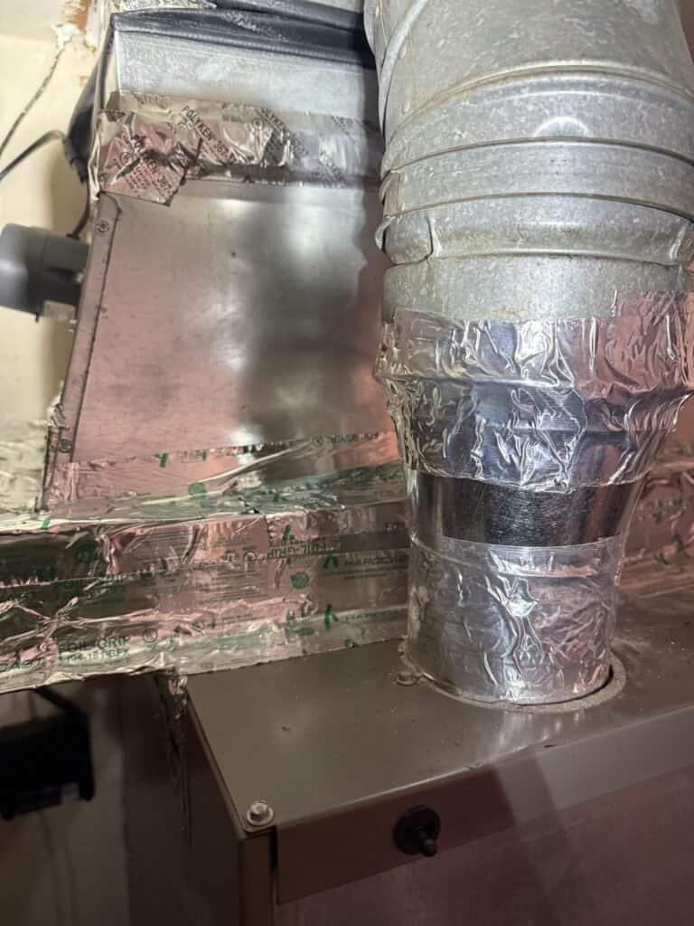 Foil-taped seams where the evaporator coil cabinet meets the ductwork in a Fort Smith home
