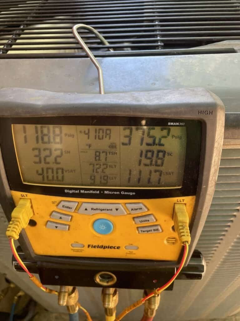 Digital refrigerant gauges showing system pressures on a Greenwood AC outdoor unit