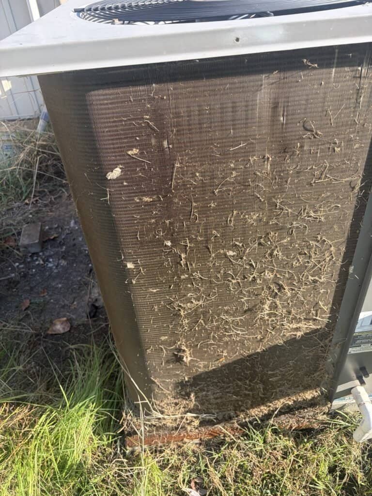 Grass and debris stuck to the outdoor coil of an air conditioner in Hackett, Arkansas