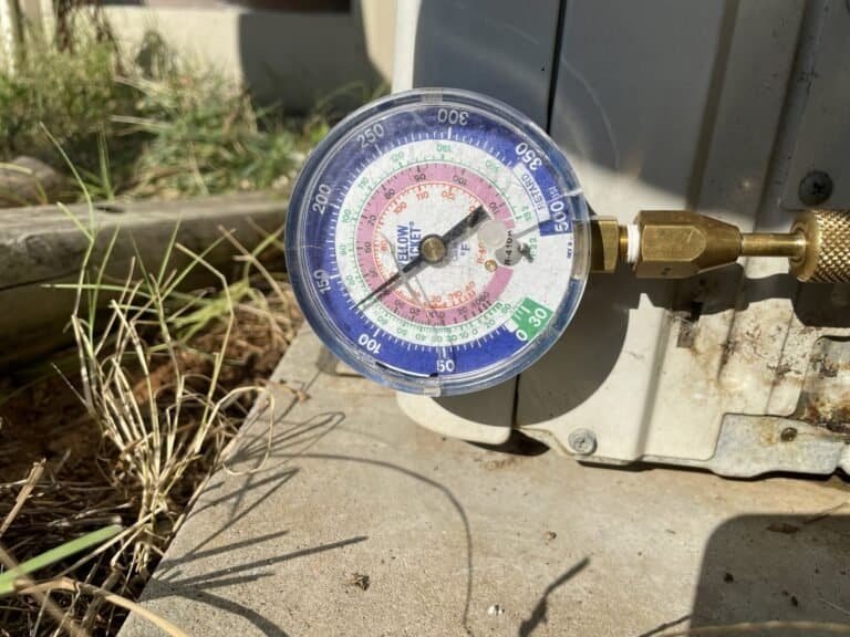 Refrigerant gauge connected to an outdoor AC unit during a tune-up in Hackett, Arkansas