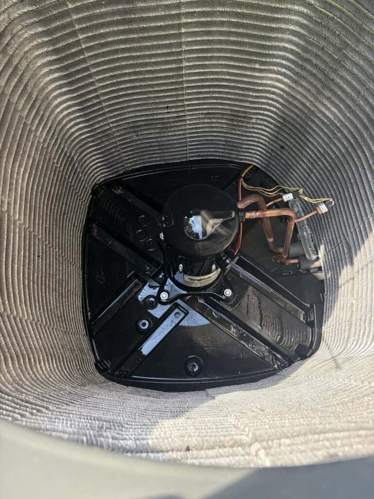 Bottom of an AC outdoor unit after cleaning during a Rudy tune-up