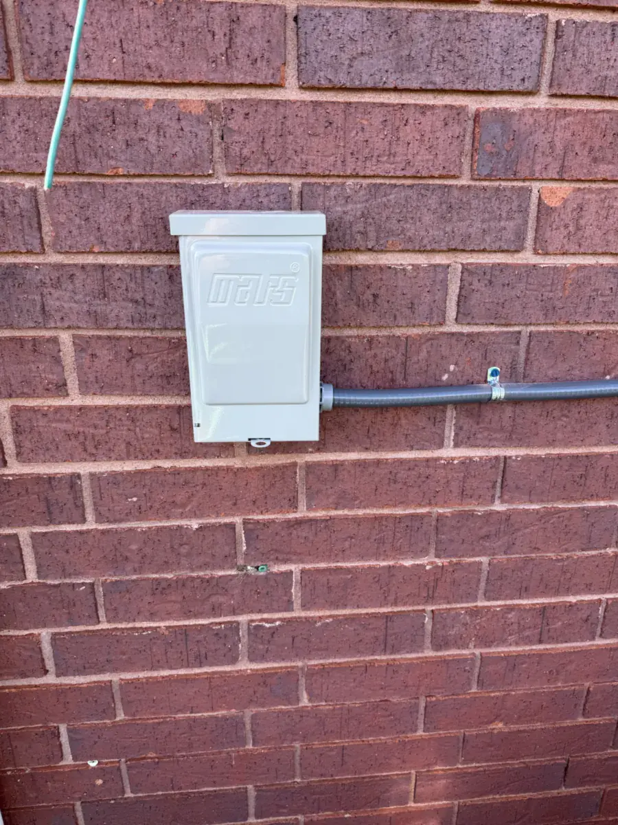 Outdoor power shutoff box mounted on a brick wall with gray conduit