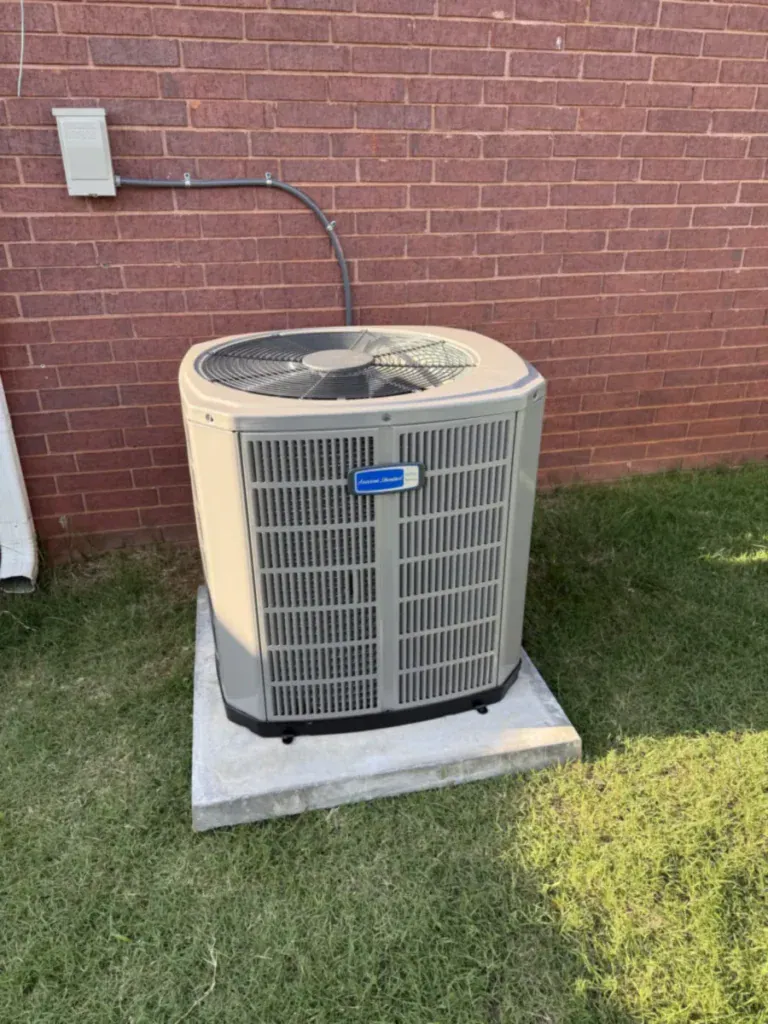 New American Standard air conditioner on a concrete pad beside a brick home in Fort Smith