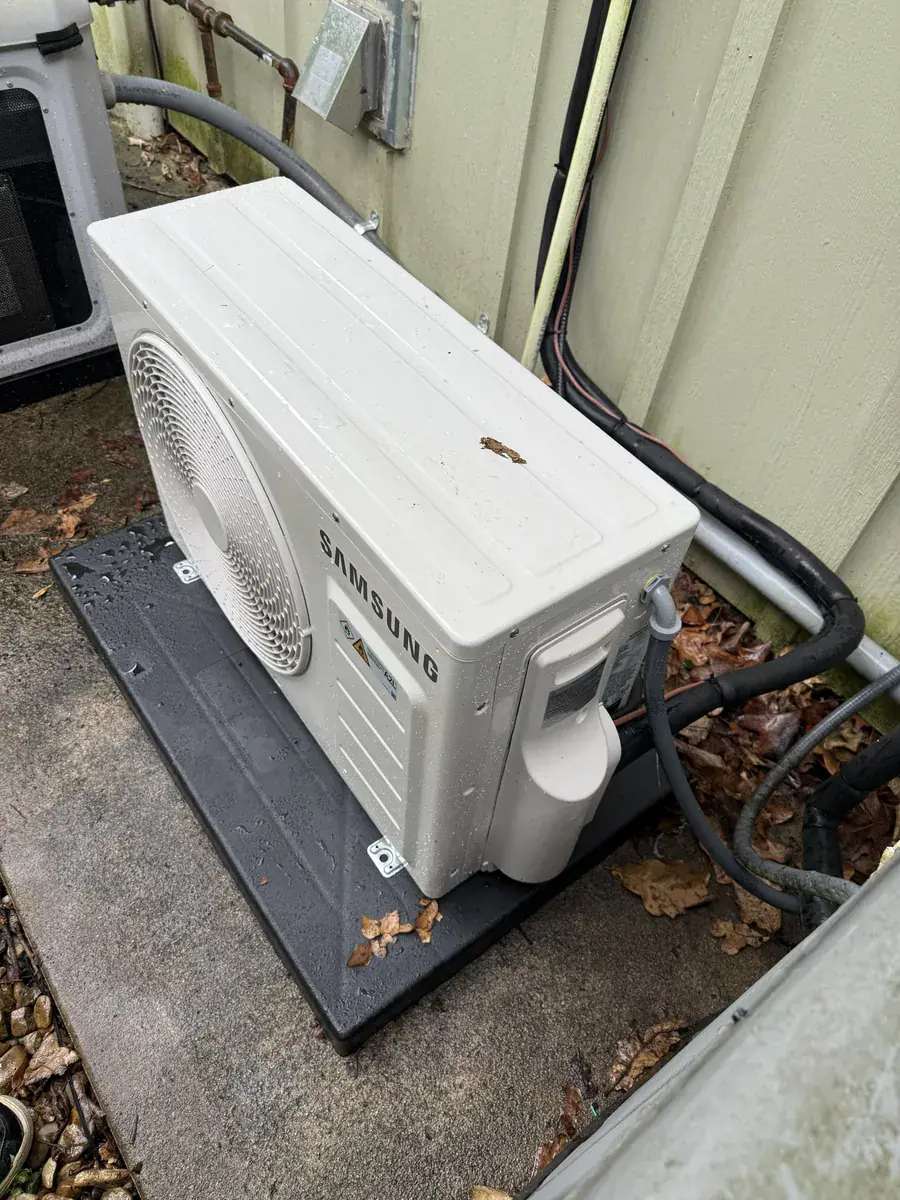 Side view of a Samsung ductless outdoor unit with insulated lines running along the wall