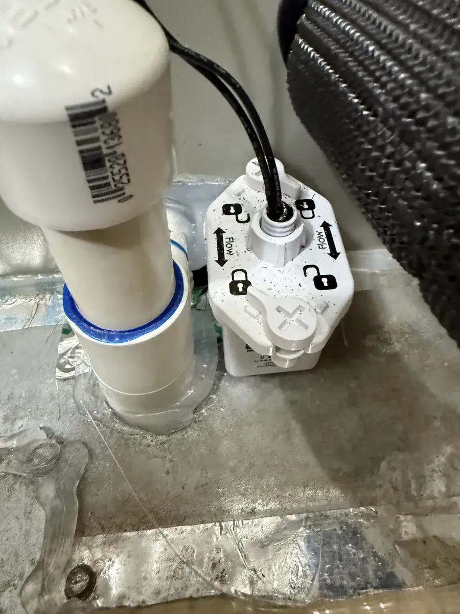 White drain safety switch attached to a drain pipe at the base of an air handler