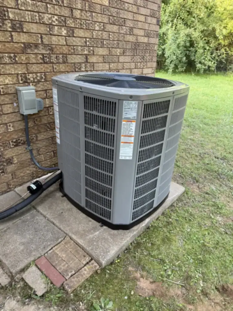 New American Standard heat pump on a concrete pad beside a brick home