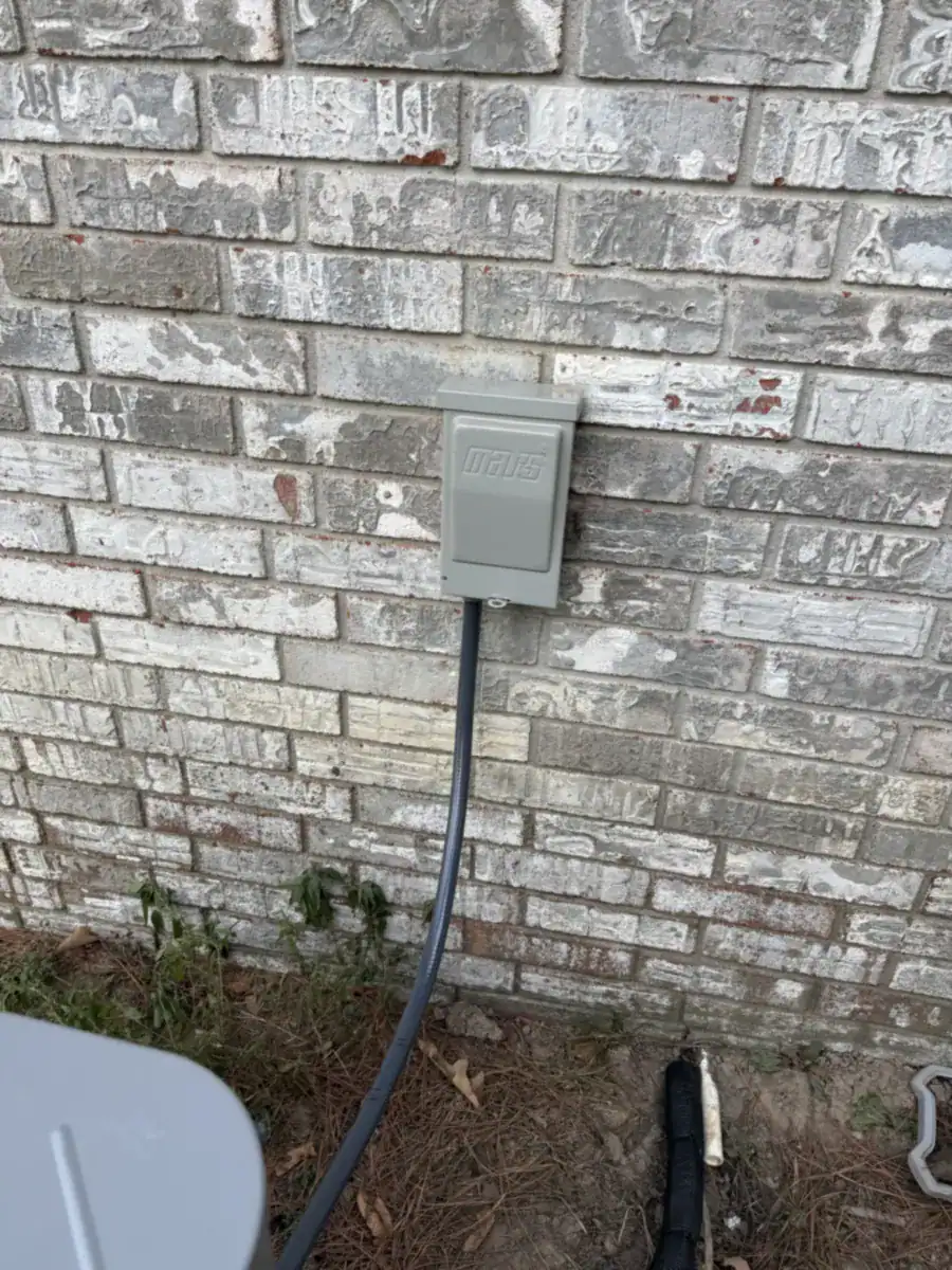 Gray outdoor power shutoff box on a painted brick wall with conduit running down